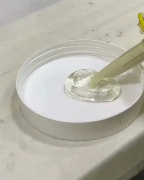 Base transparente da cola sendo colocada num pote branco